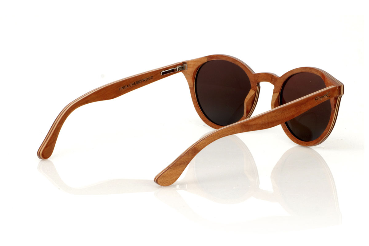 Wood eyewear of Cherry LINDA. The LINDA wooden sunglasses come with a rounded and elegant silhouette, standing out for their cross-laminated cherry wood frame, which not only guarantees durability but also a unique style thanks to its beautiful grain. Silver metal pins on the front add a touch of class, balancing the warmth of the wood with a subtle shine. With tighter measurements of 140x49 and a caliber of 48, these glasses offer a comfortable fit and versatile style, perfect for those looking for a sophisticated and timeless accessory. for Wholesale & Retail | Root Sunglasses® 